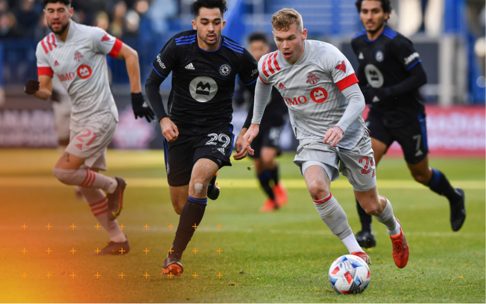 Footballers trying to dribble the ball past opposing team members